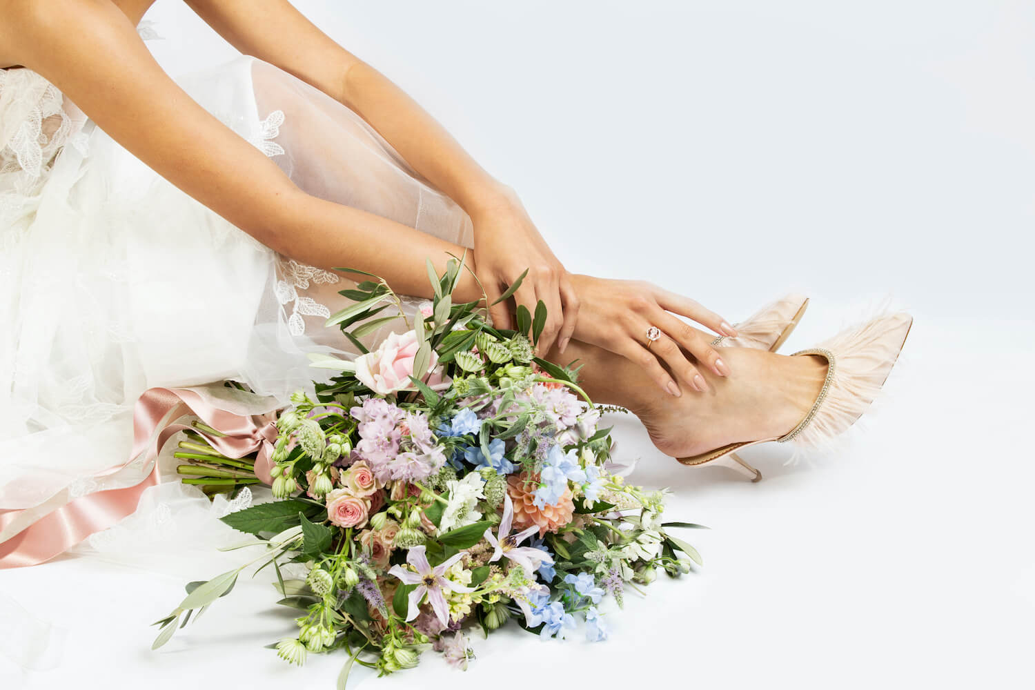 bride seated with feet out wearing her dream wedding shoes and flowers at her side