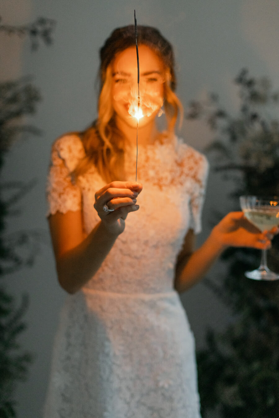 smiling bride wearing a wedding dress, holding champagne and a candle 
